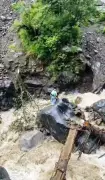 Father crosses raging stream with child tied to back in Kullu